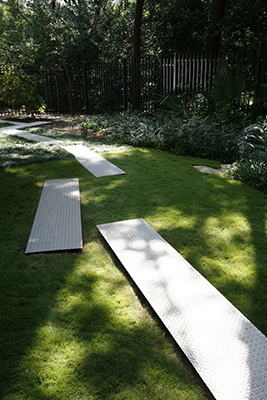 A lawn path made of long rectangles of diamond patterned sheet metal laid out in an irregular path