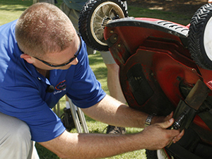 Man working on underside of mower