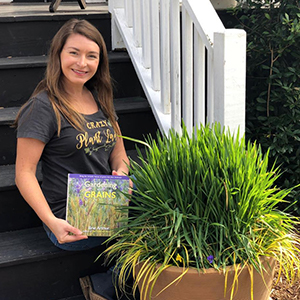 Woman sitting on front steps with her book and a potted rice plant