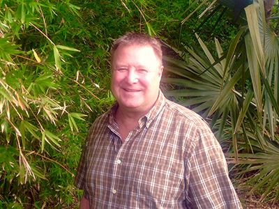 Photo of Terry Wawrzyniak in front of saw palmettos and bamboo plants