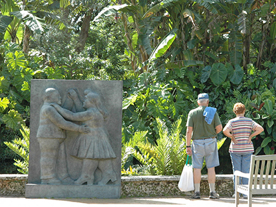Vistors looking at the tropical plants next to relief-style statue of a couple dancing