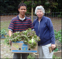 A young man and woman stand with vegetables in the garden