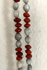 Photo of a necklace made of red and gray seeds strung like beads.