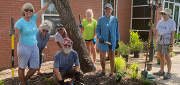 Volunteers posing with their garden tools in a newly installed landscape