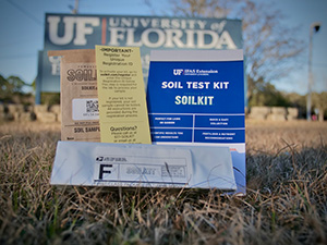 A soil testing kit sitting on the ground in front of a UF campus sign.