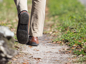 View of feet in dress shoes walking along a dirt path