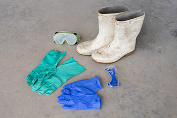 Two different pairs of latex gloves, two pairs of safety googles, and a pair of white rubber boots