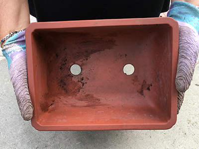an empty terracotta container with holes in the bottom