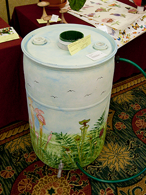 A rain barrel decorated with a landscape scene
