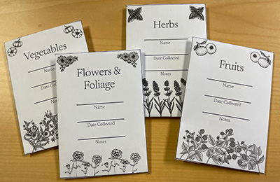 Four black and white printed seed packets each with a corresponding design: vegetables, flowers and foliage, herbs, and fruits