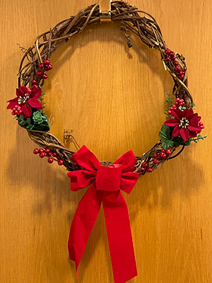 A grapevine wreath with simple holiday decorations like a red bow and fake poinsetta flowers