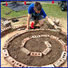 Young man kneeling over the beginning layout of a spiral garden