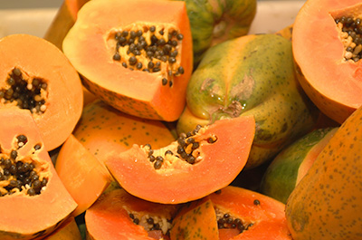 papayas cut open to reveal dark orange flesh and dark brown seeds