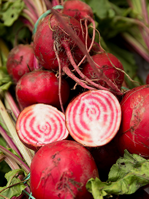 Red beets, one cut in half to expose the white flesh with red concentric circles