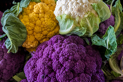 three differently colored heads of cauliflower, orange, white, and purple