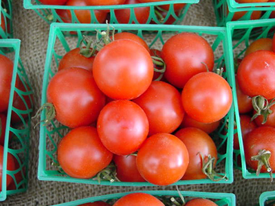 Round cherry tomatoes in a small green basket