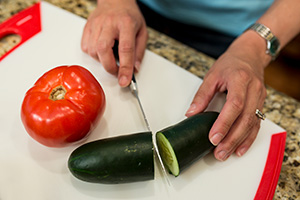 A cucumber being cut in half on a cutting board