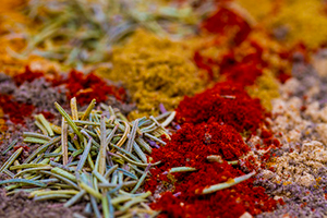 Small, colorful piles of turmeric, cumin, and dried rosemary