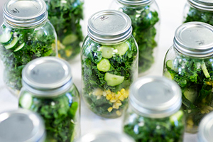Glass Mason jars full of greens and other raw vegetables for salad