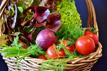 Basket full of vegetables like tomatoes and red lettuce