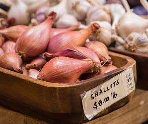 Shallots for sale in a small wooden tray