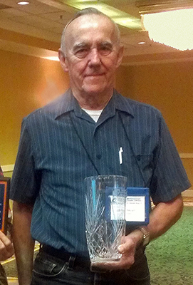 Older man standing and holding crystal vase award