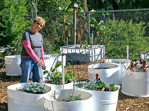 Woman in garden surrounded by white plastic tubs each full of plants