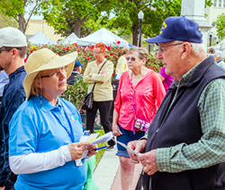 Lady in blue shirt and straw hat talking to an older gentleman outside