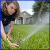 Lady adjusting a sprinkler head in a lush St. Augustinegrass lawn