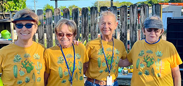 Four smiling women wearing matching yellow t-shirts