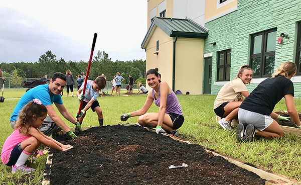 A smiling family working over a raised garden bed