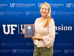 Smiling woman holding plaque.