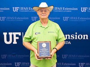 Man in cowboy hat holding plaque.