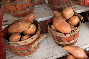 Wooden baskets of sweet potatoes for sale at farmers market.