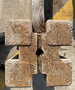 Close view of a special concrete form that holds a two-by-four above the ground.