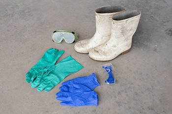Two different pairs of latex gloves, two pairs of safety googles, and a pair of white rubber boots