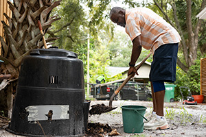 Man using shovel to put leaves in a composter