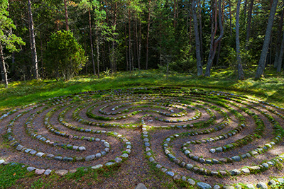 A rustic labyrinth, a circular path laid out with stones in a green space.