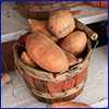 A wooden basket full of sweet potatoes for sale.