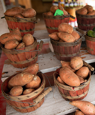 Sweet potatoes in wooden baskets for sale at a farmers market