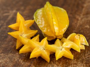 Yellow, waxy carambola fruit, with cut slices showing its star shape.