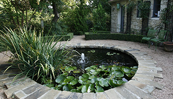 A small shaded pond fully enclosed by a home patio.