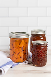 Three mason jars each filled with preserved vegetables.