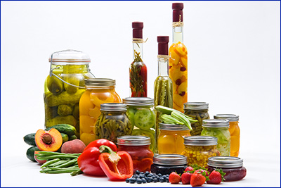 An attractive selection of preserved food in glass jars and vinegar bottles.