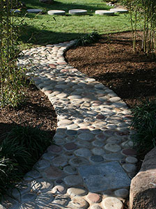 A stone path cuts through a mulch landscape bed